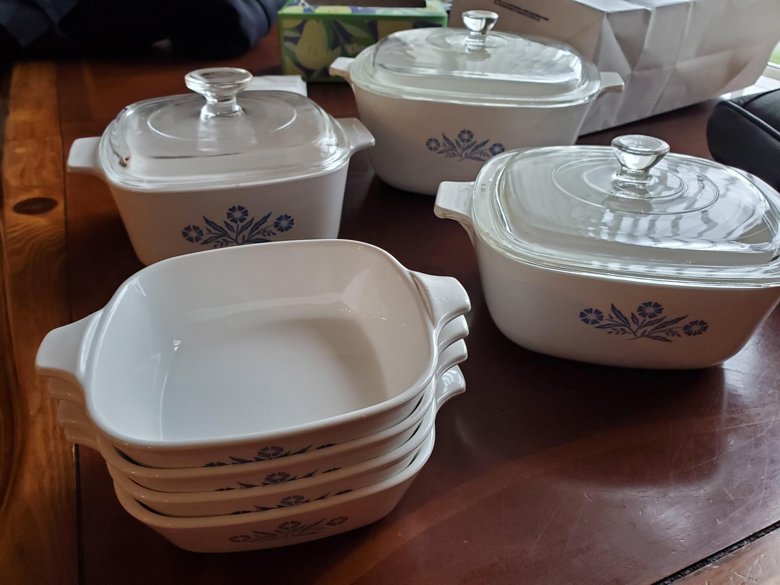 Hands carefully placing a piece of Corningware into a clean modern kitchen oven.
