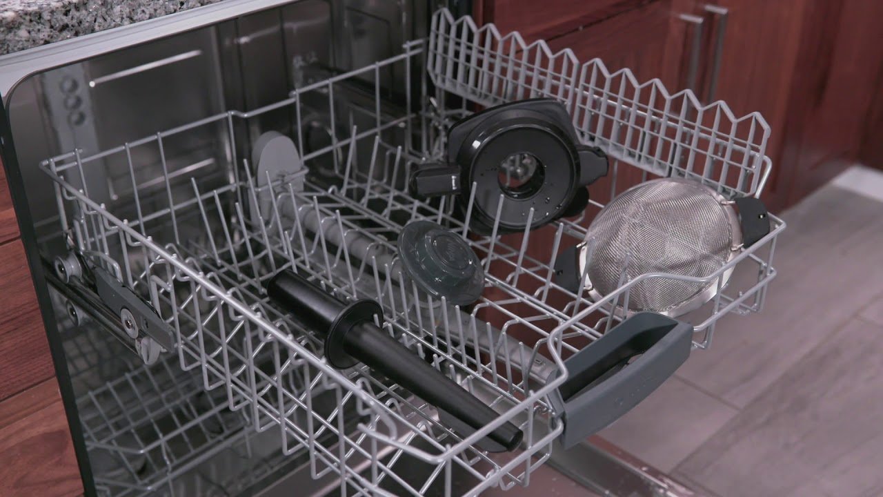A person wipes down a disassembled Ninja blender base with a cloth.