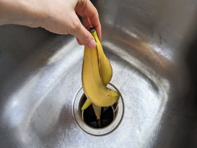 Thin strips of orange peel prepared for safe disposal in a kitchen sink.