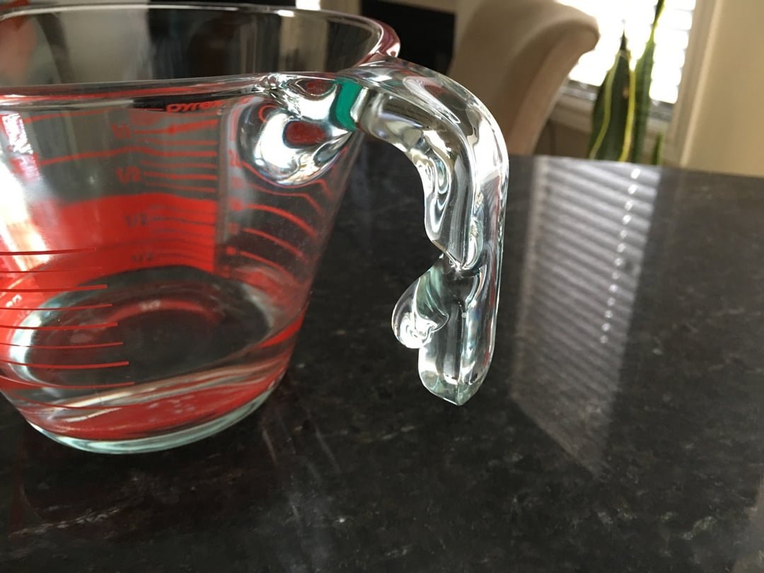 A clean glass food container sits on a counter, ready for microwave safe heating.