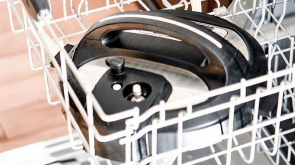 A cracked plastic handle on a pressure cooker lid indicating potential safety concerns.