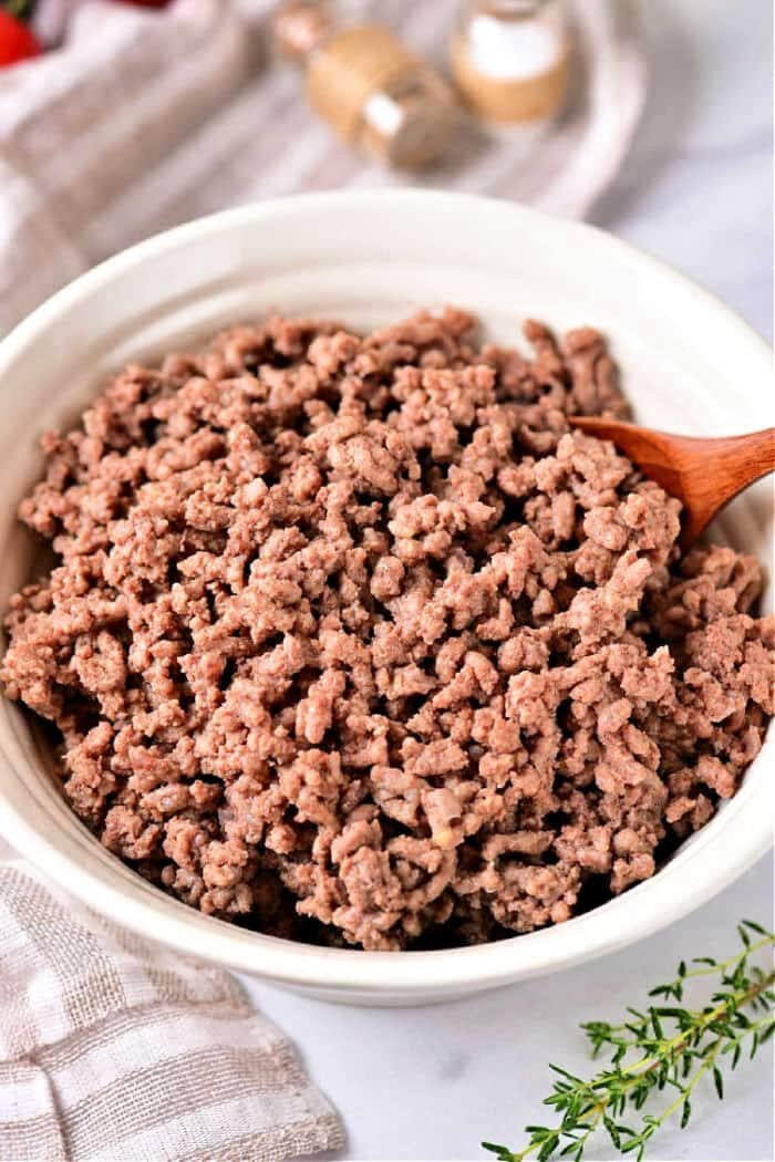 Small chunks of raw ground beef arranged in a glass bowl for microwaving.