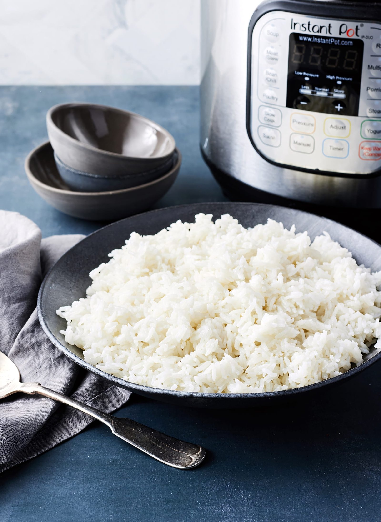 A bowl of fluffy cooked rice sitting next to a rice cooker.