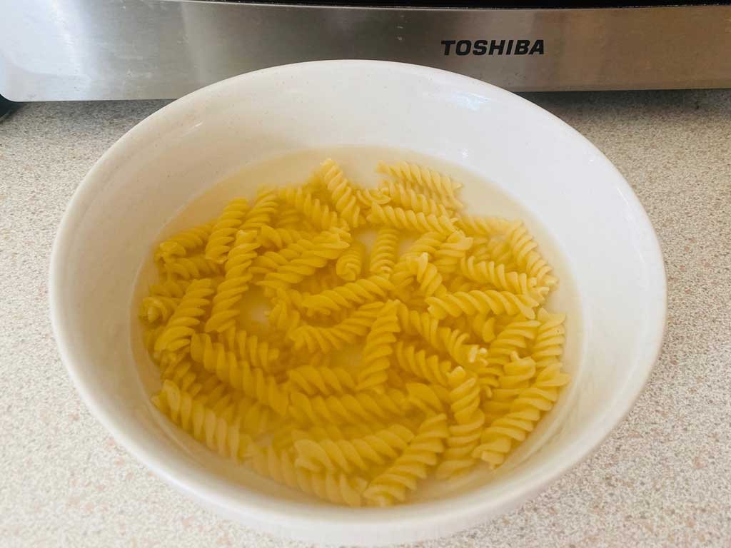 A variety of dry pasta shapes arranged neatly on a modern kitchen counter.