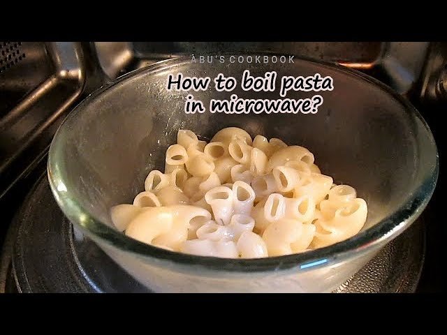 Dry penne pasta submerged in a glass bowl ready for microwave cooking.