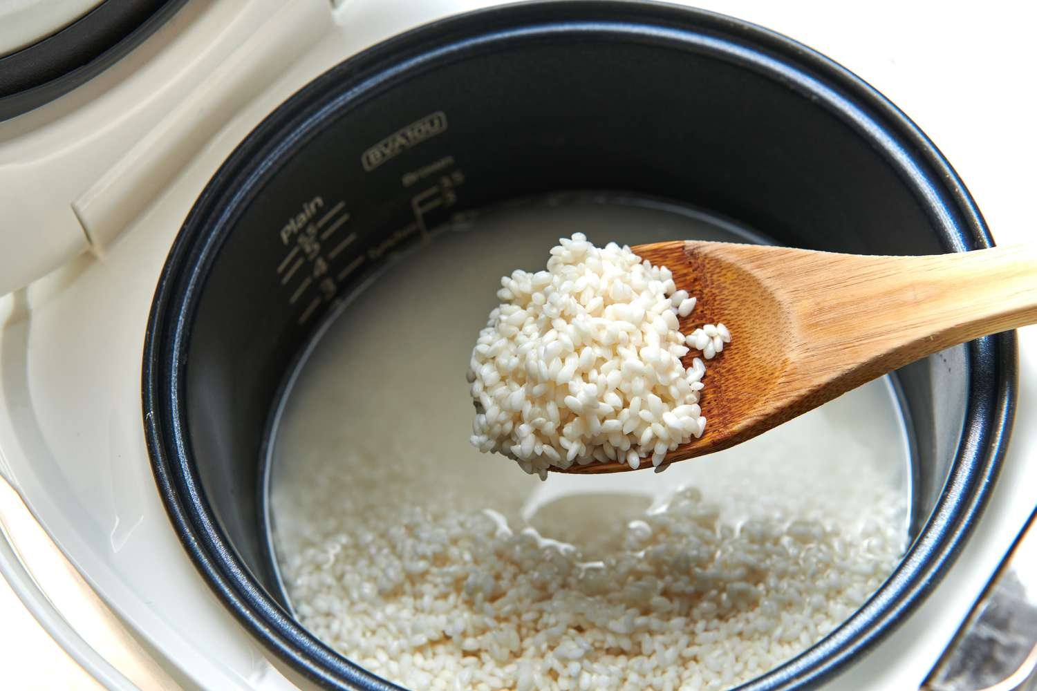 A modern rice cooker filled with perfectly cooked glutinous sticky rice on a counter.