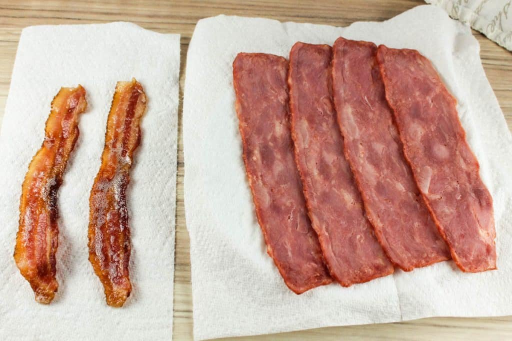 Three strips of raw turkey bacon arranged neatly on a white kitchen plate.