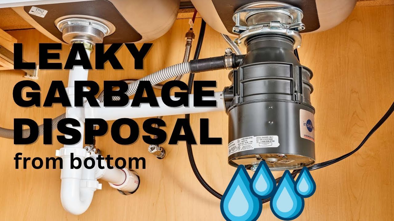 A close-up of a leaking garbage disposal unit under a kitchen sink.
