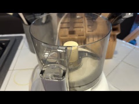 Coarsely ground coffee beans in a food processor bowl next to a French press.