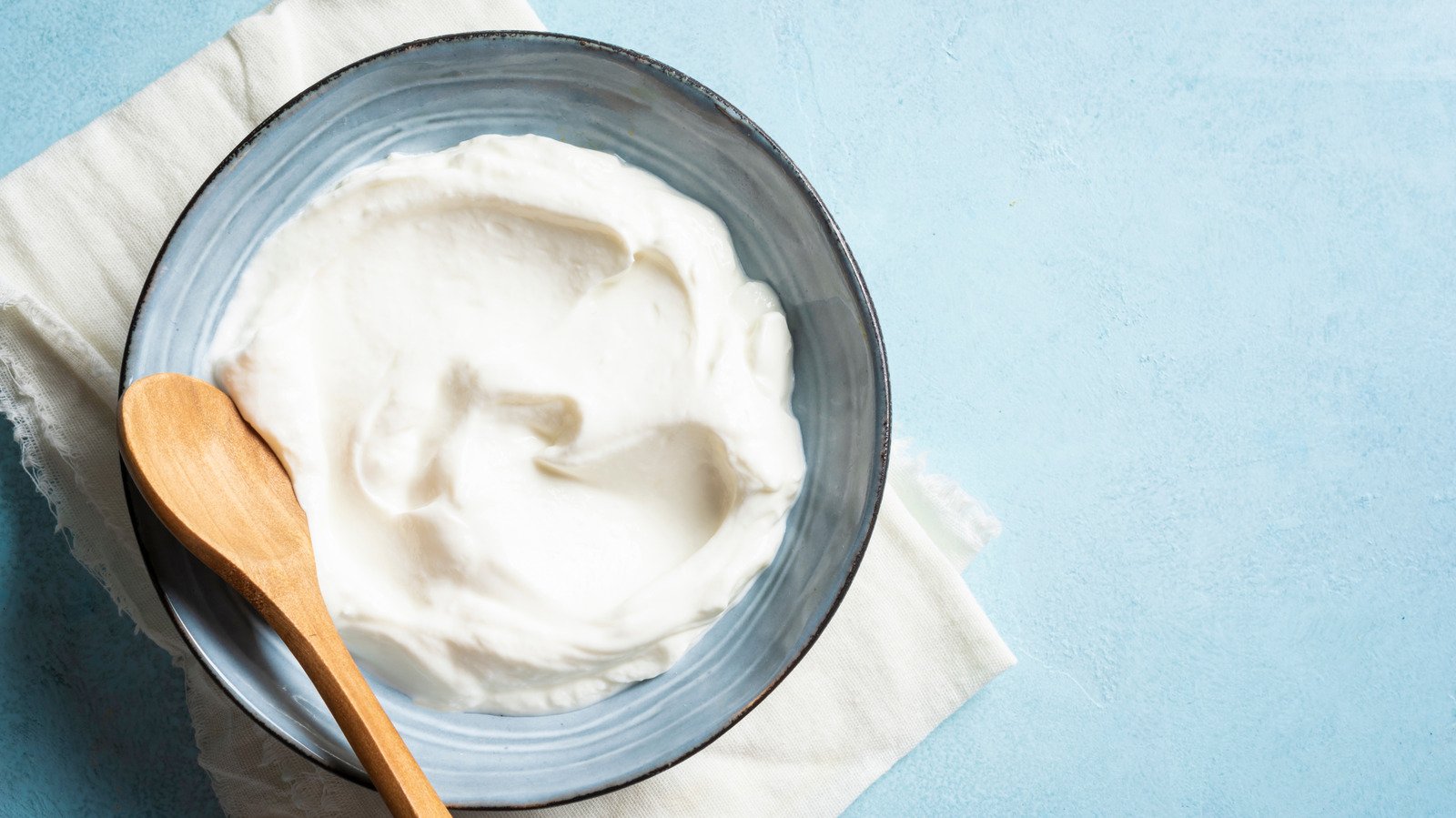 A small ceramic bowl of sour cream placed inside a clean microwave for heating.