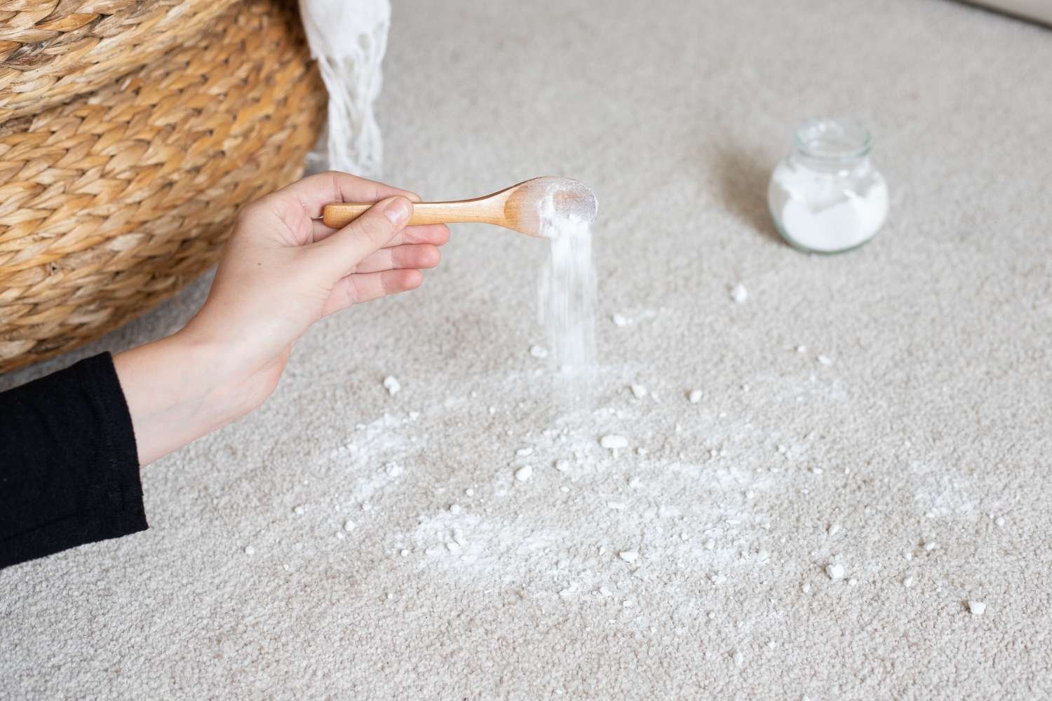 Baking soda being sprinkled onto dry synthetic carpet to neutralize household odors effectively.