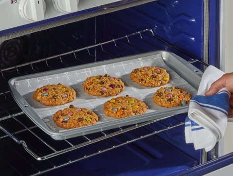 A slice of pizza on parchment paper inside a microwave for safe reheating.